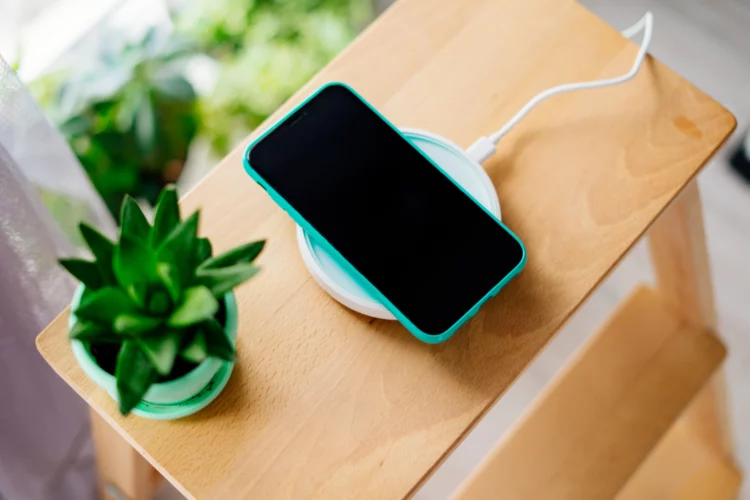Smartphone in mint silicone case is charged from a wireless charger.