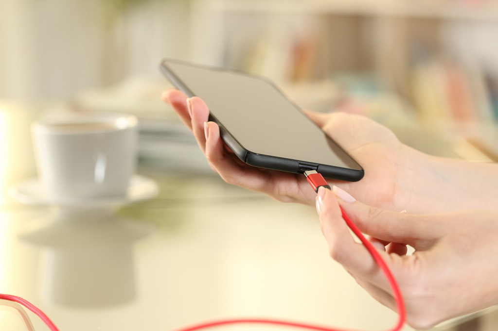 Woman hand plugging battery charger on phone.