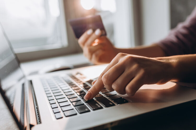 female hands hold a credit card while using the laptop