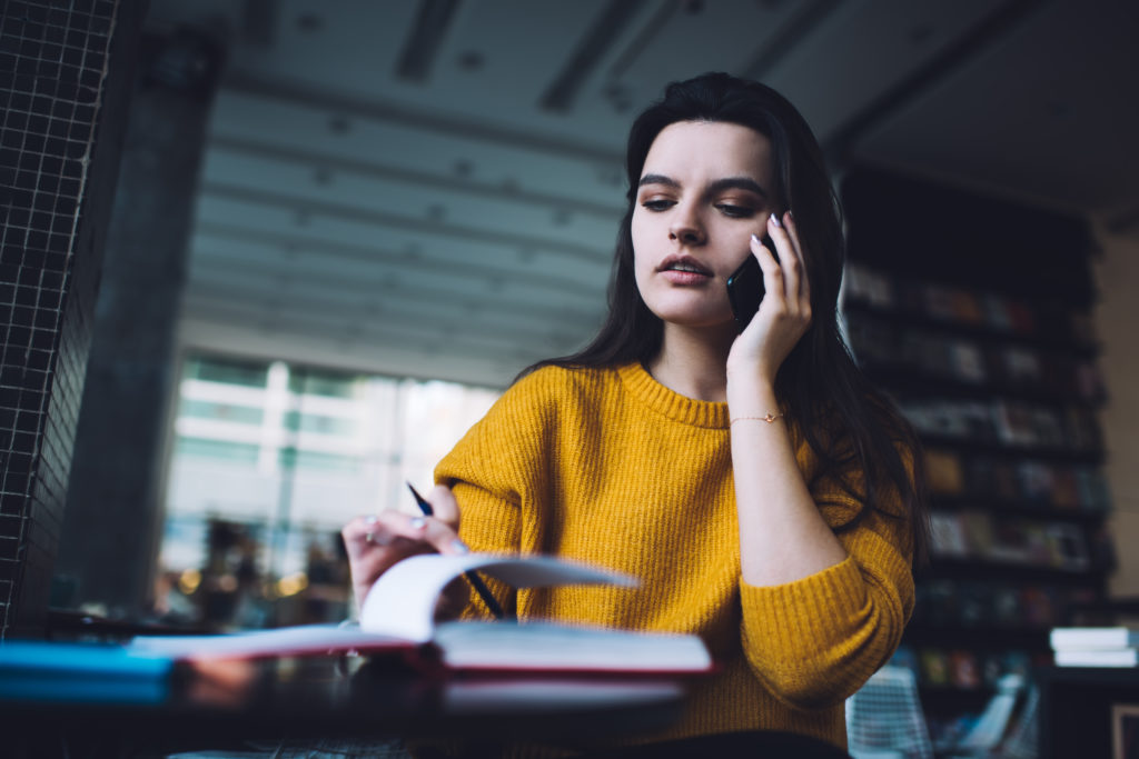 Young female assistant communicating on cellphone.