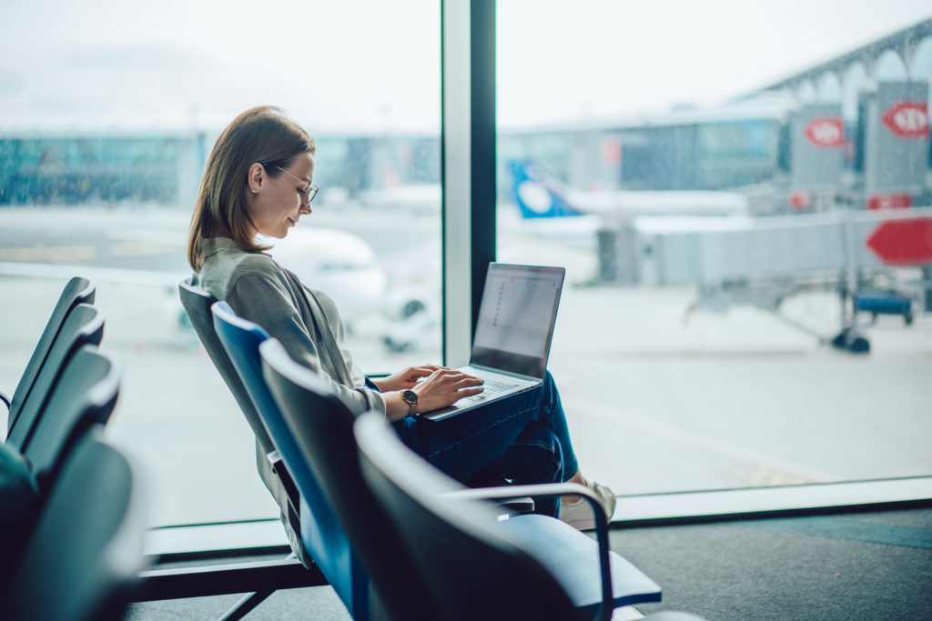 Attractive female traveler using laptop at the airport.