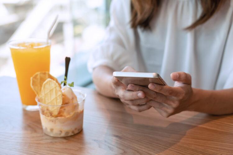 Young woman using smart phone and enjoy eating dessert in cafe
