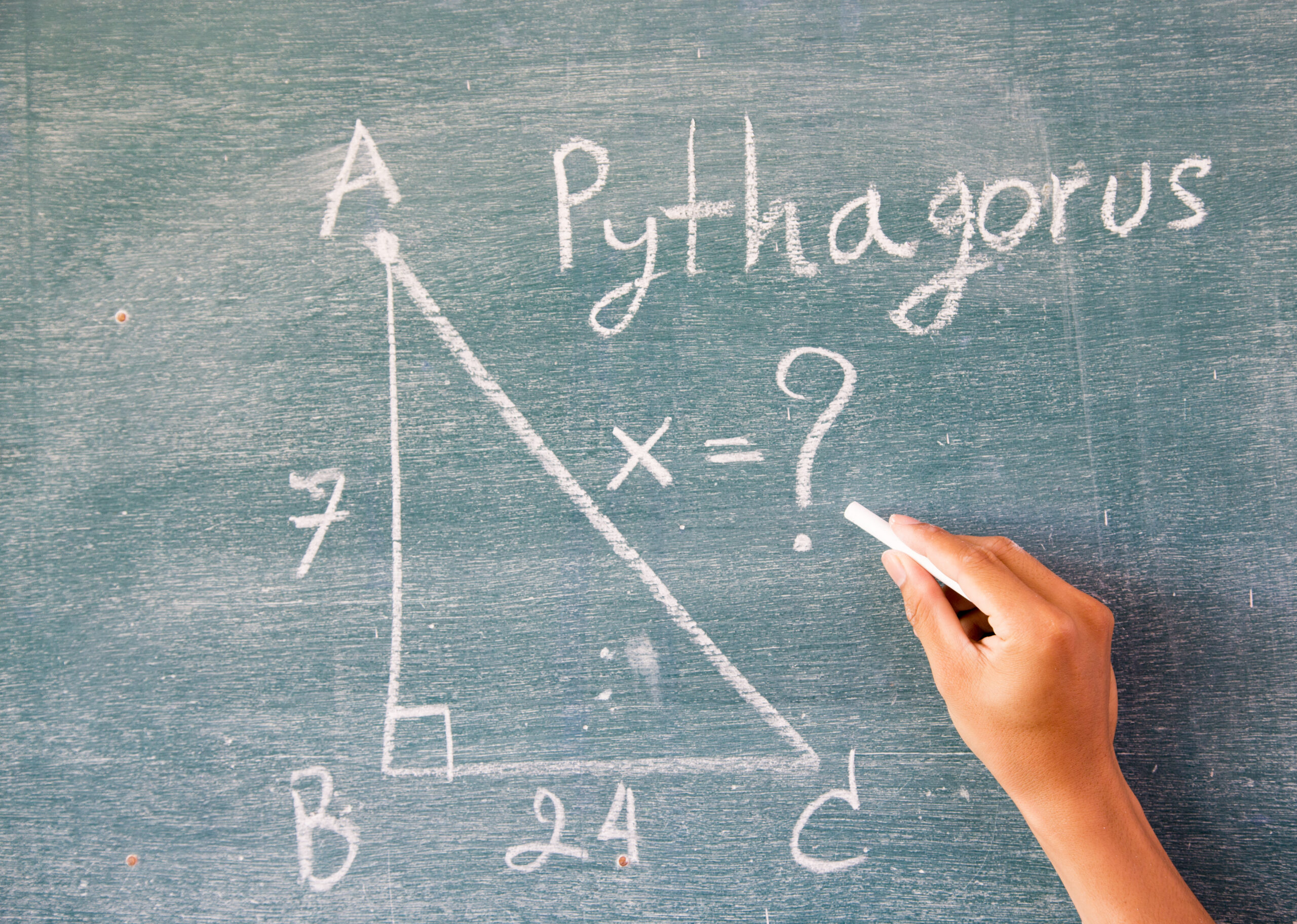 female hand writing answering a math problem on the blackboard using white chalk