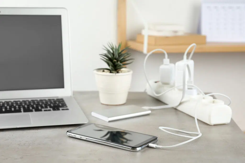 Devices charging with cable on light stone table.