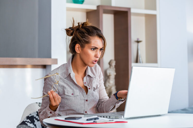 woman working with laptop at home or modern office with confused look.