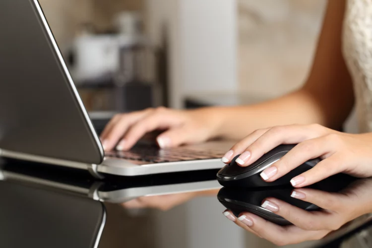 Woman hands working with a laptop and a mouse