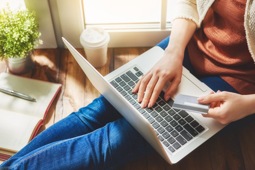 Young woman shopping online holding a credit card.