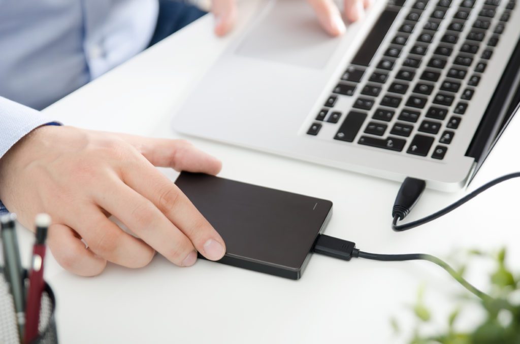 Black external hard disk drive connected to a laptop.