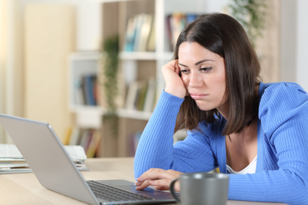 Bored woman checking her laptop on a desk at home.