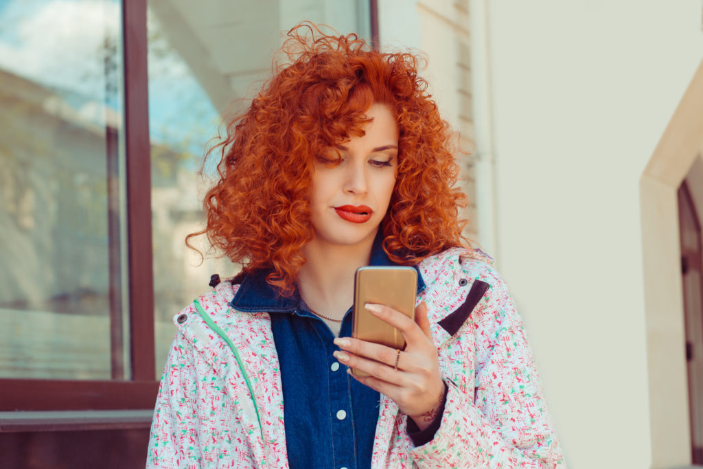 A bored woman using phone outdoors.