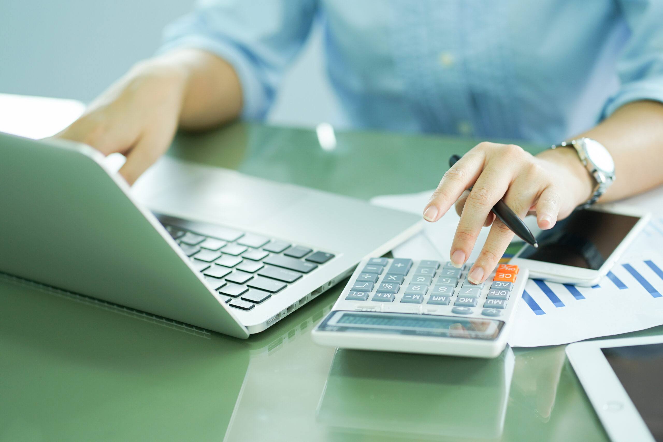 woman working on laptop, using calculator for computing