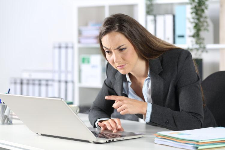 Suspicious executive reading on laptop at the office