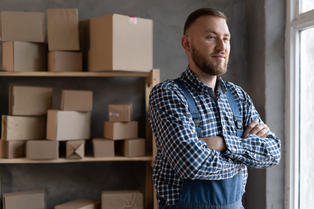 Business owner stands near boxes of stocks.