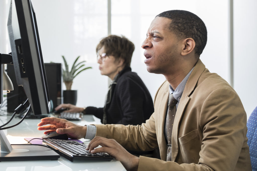 Businessman squinting his eyes and getting frustrated at the computer.