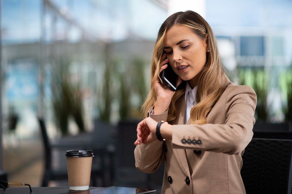 Woman looking at her watch while making a phone call.