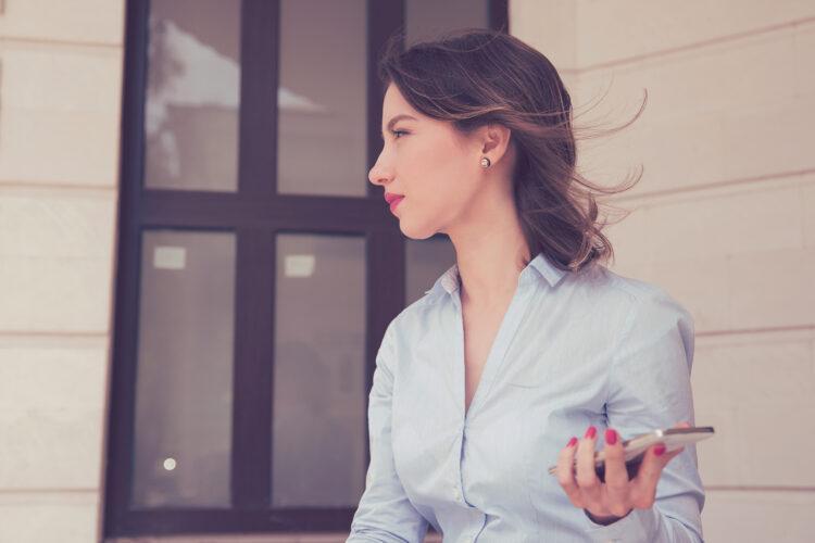 Frustrated annoyed sad woman with mobile phone standing outside