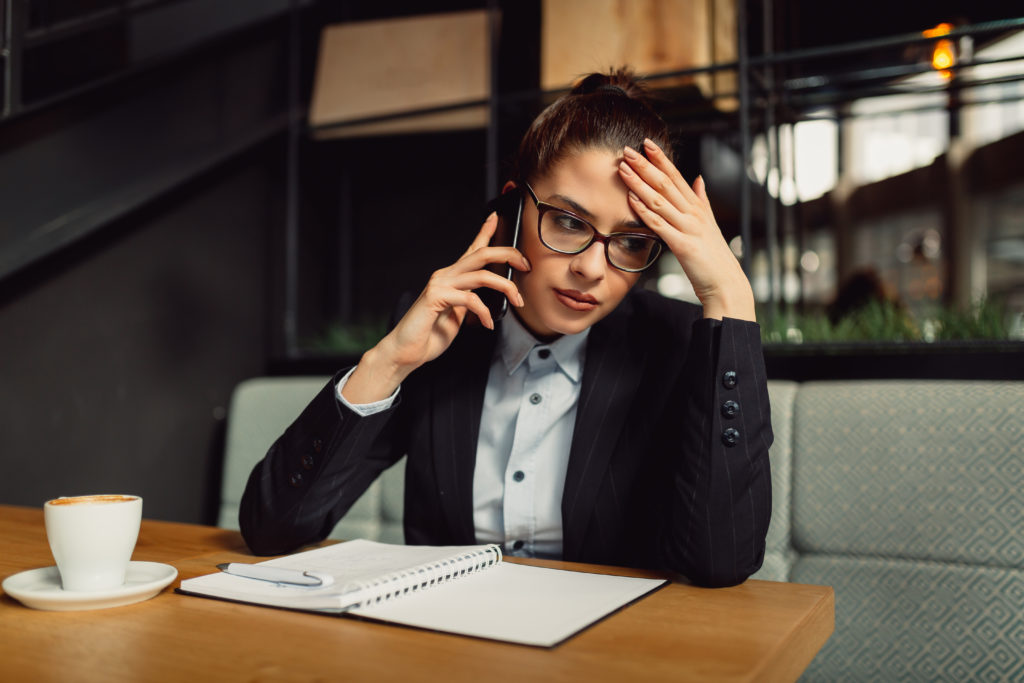 Worried businesswoman with eyeglasses holding smart phone