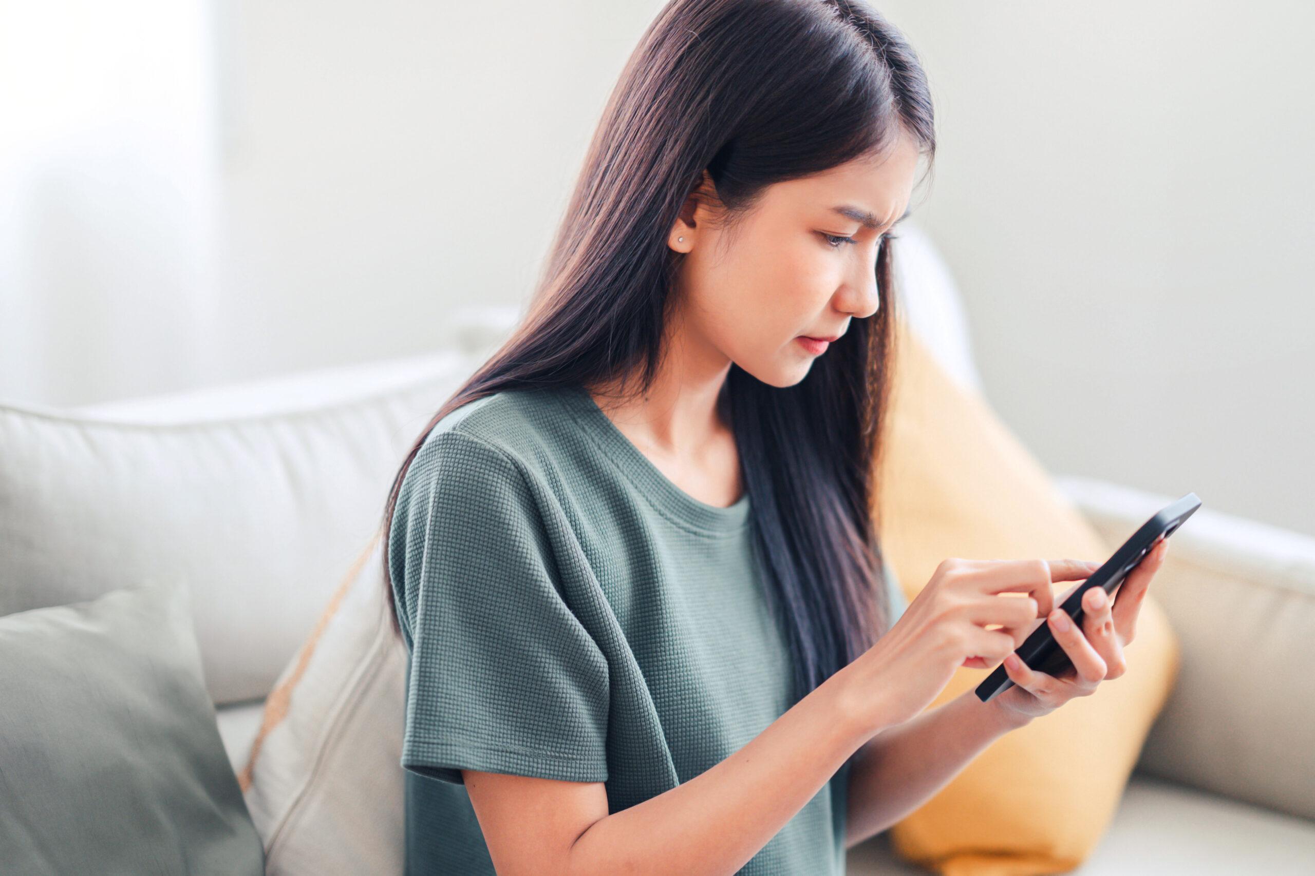 Worried young woman looking at smartphone