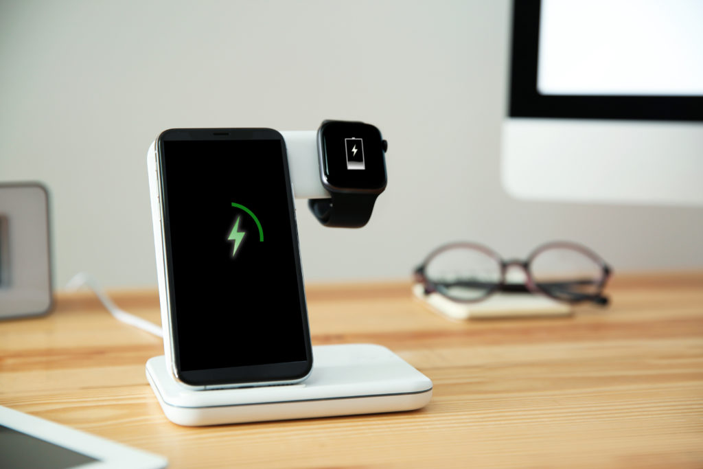 Mobile phone and smartwatch on a wireless charger.