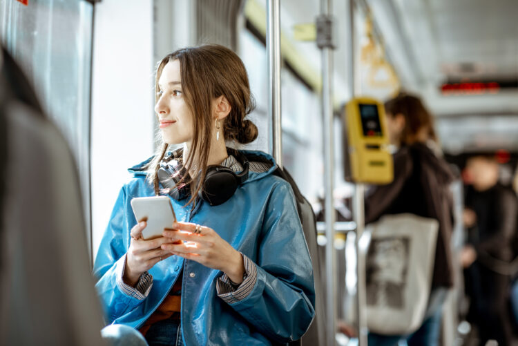 Female passenger riding a bus listening to music via headphones.
