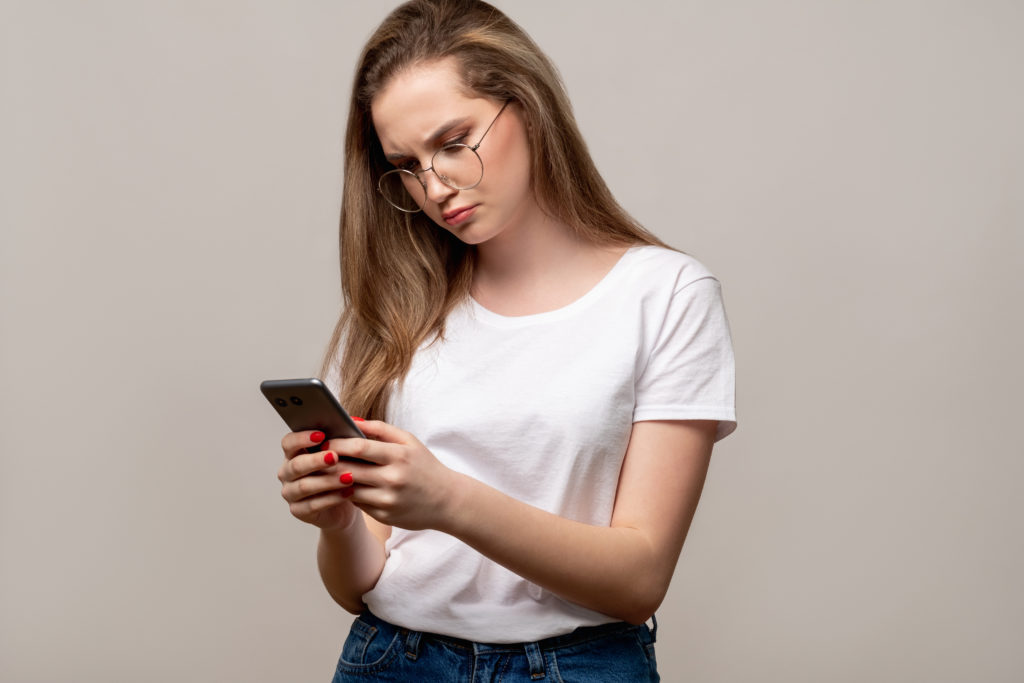 Woman looking annoyed, looking at smartphone in hand