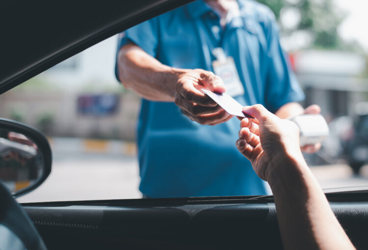 Man driving car hand holding credit card for payment.