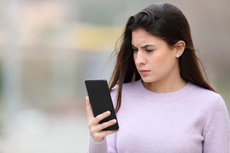 Worried woman reads phone in the street
