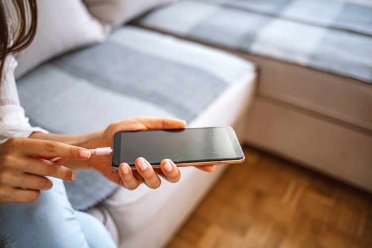 Female hands plugging a charger in a smart phone in the living room