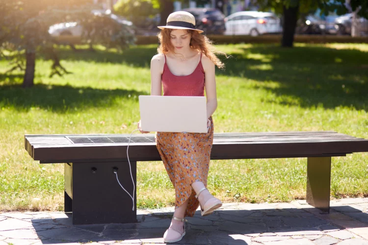 woman charging laptop outdoors at an innovative solar powered outdoor charging station