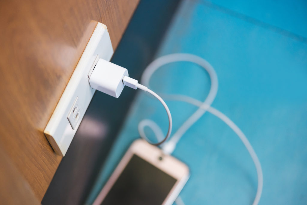 Charging smartphone in a public space, blue floor.