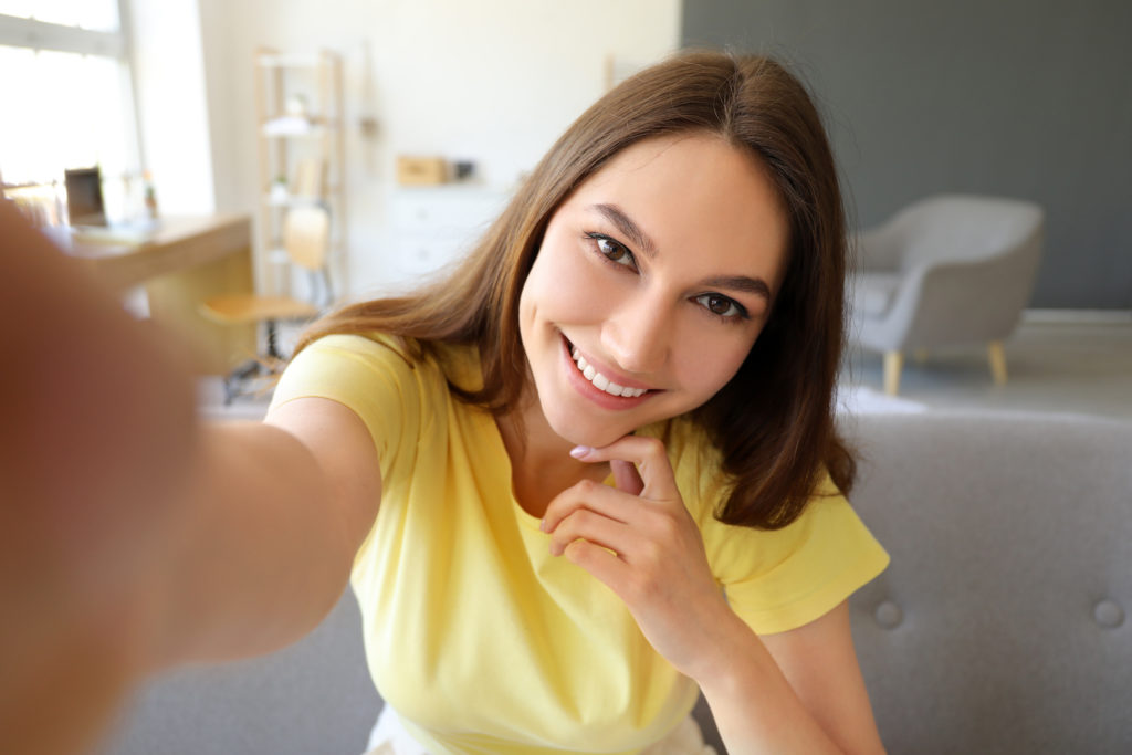 Young smiling woman taking selfie at home