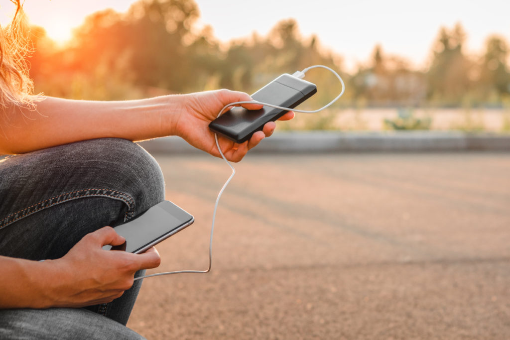 Woman charging her phone using a power bank.