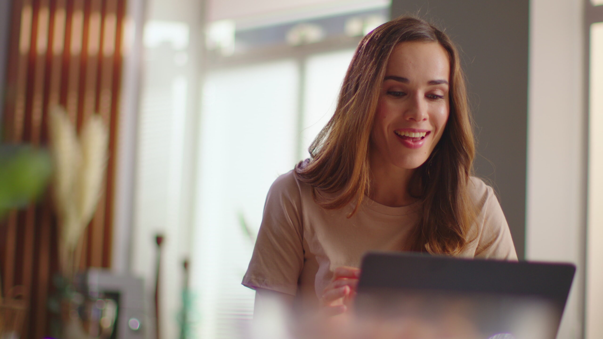 woman looks pleased and relieved looking at laptop screen