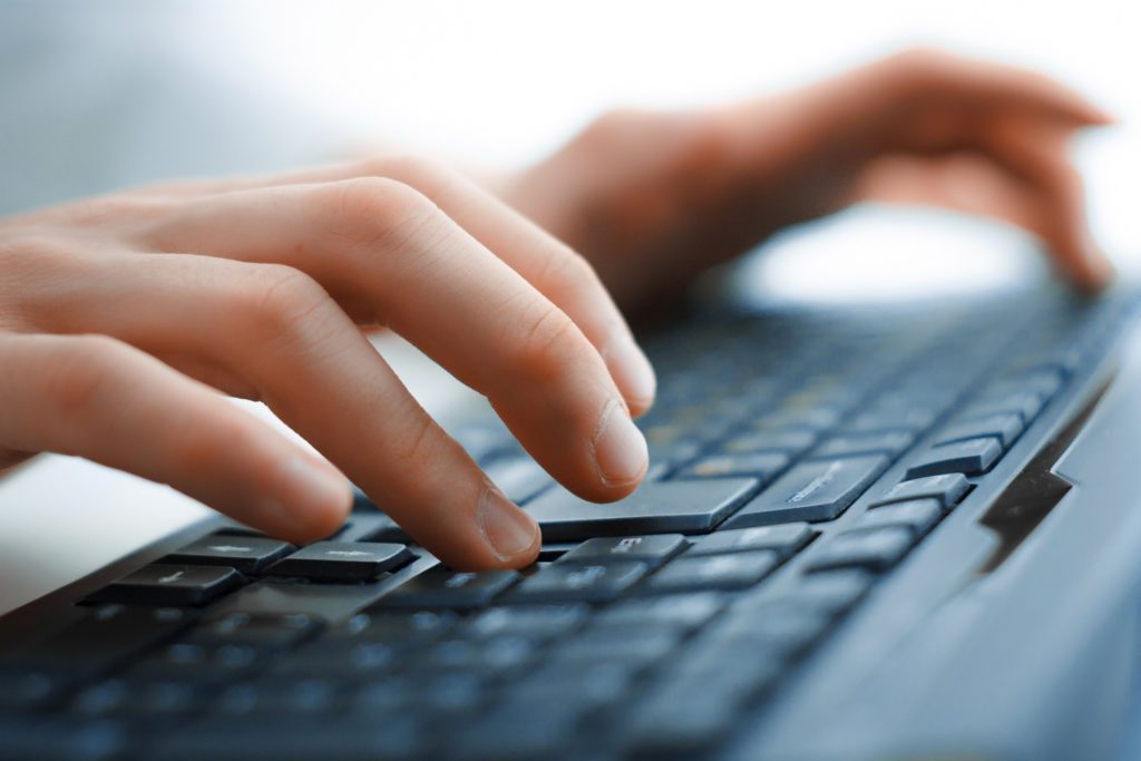 Close-up of female hands typing on a keyboard.