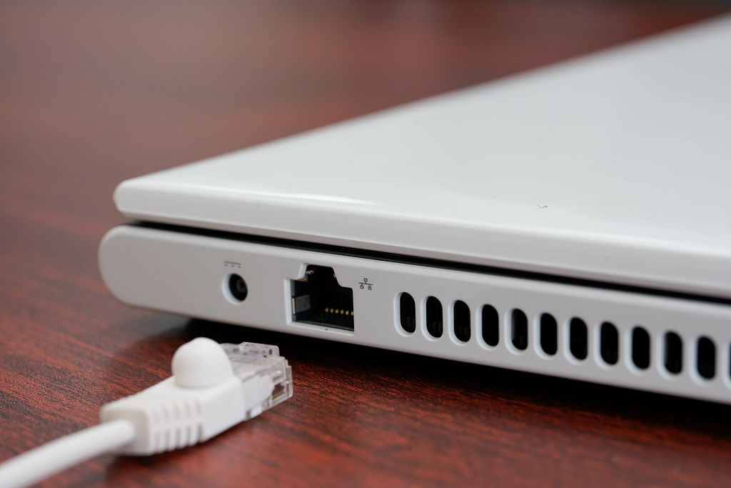 Unplugged white ethernet cable next to the laptop port.