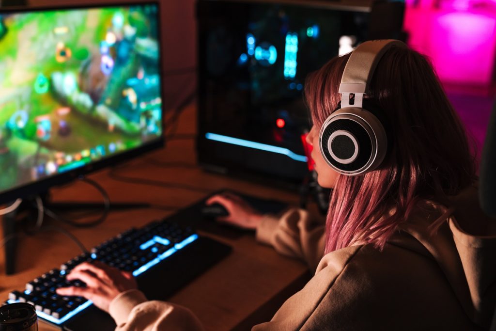 Girl focused on playing video game on personal computer.