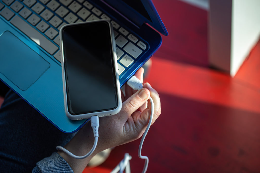 The smartphone is connected to the laptop via USB cable.