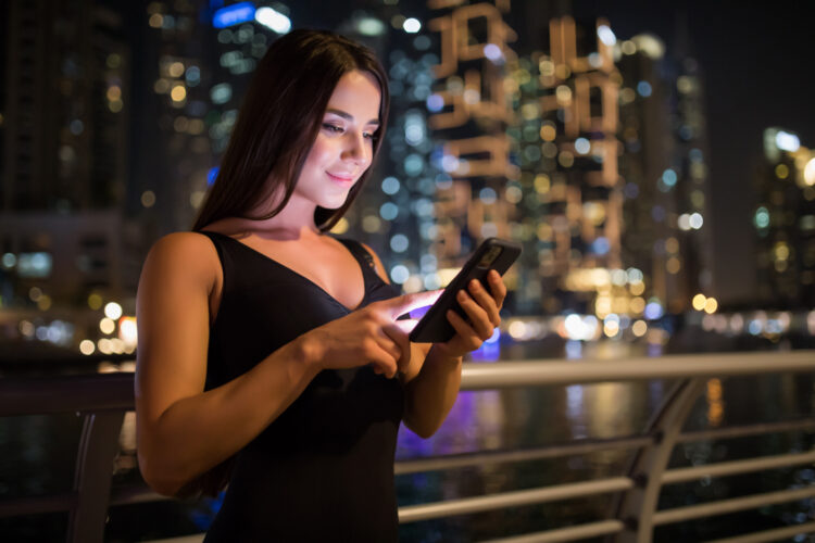 Young woman using cell phone in city at night