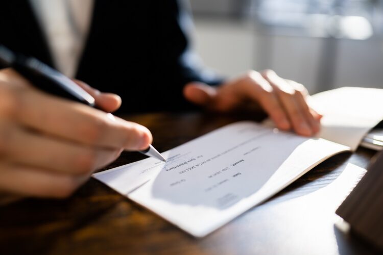 Hand signing a money cheque.