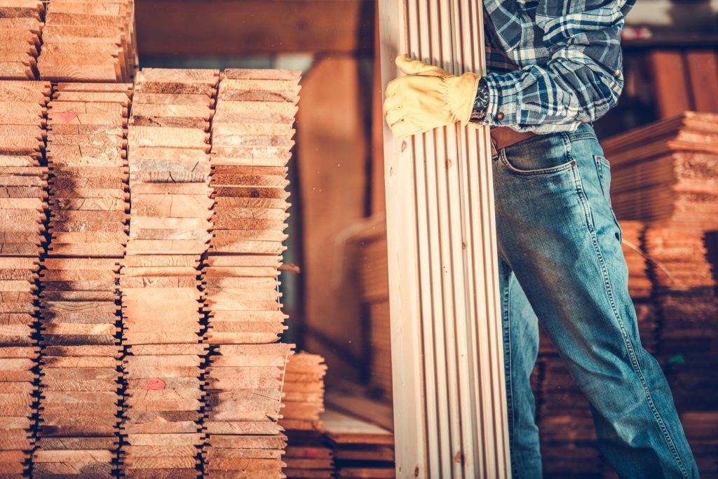 Contractor with Planks. Caucasian Carpenter with Pile of Wood Boards. Construction Materials Theme.