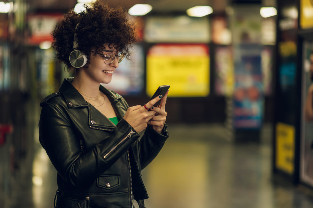 Woman on headphones while using her mobile phone.