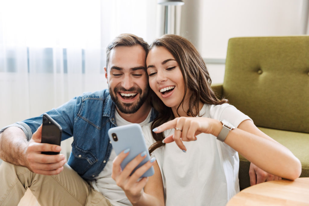 Young couple looking at their phones at home.