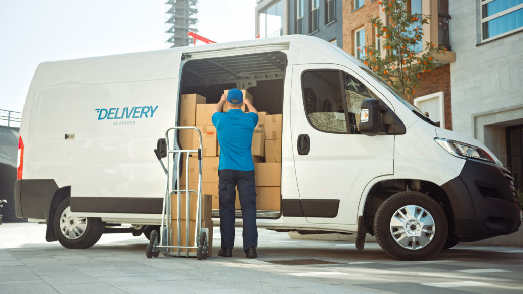 Delivery man uses hand truck trolley full of cardboard boxes.