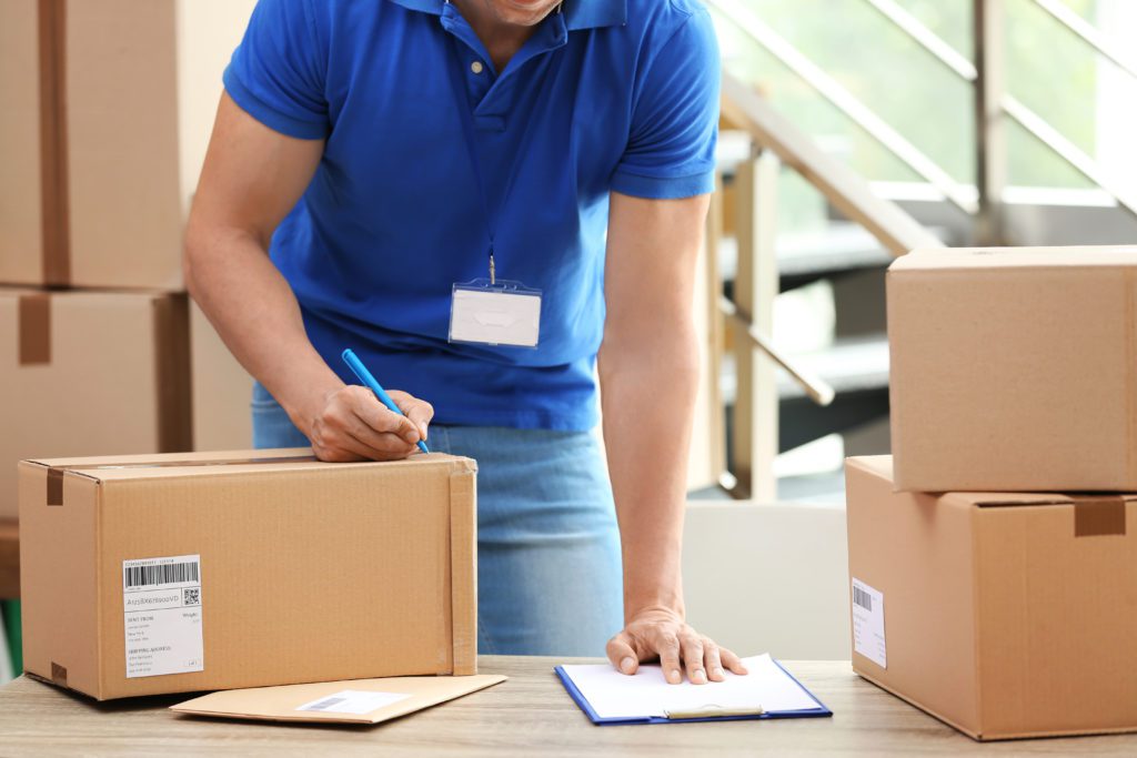 Courier staff taking notes on parcel for delivery.