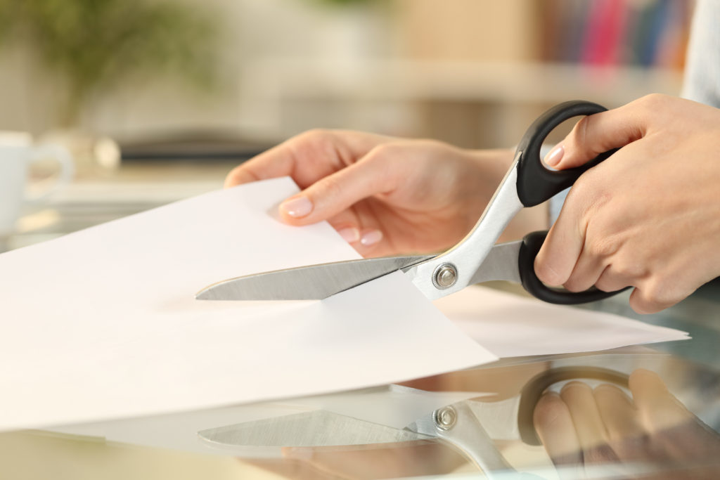Woman hands with scissors cutting paper on a desk