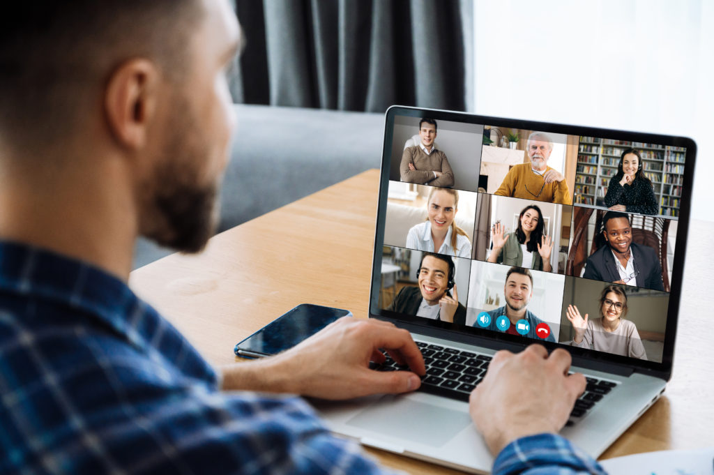 Man using laptop while having an online meeting with coworkers.