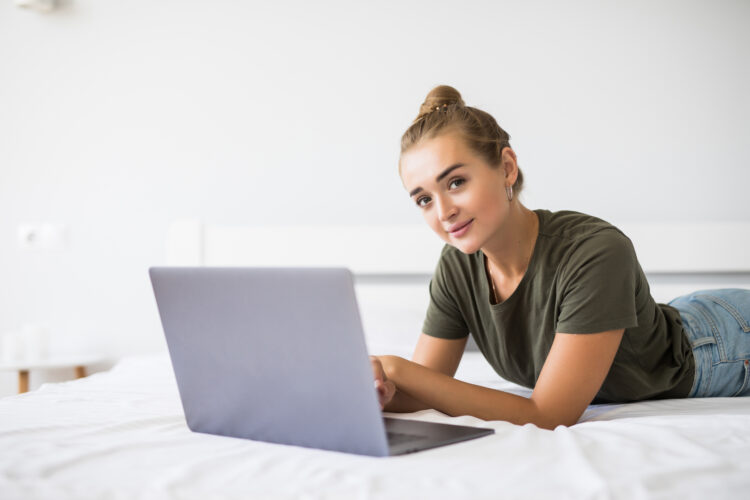 young woman using laptop in bed at home