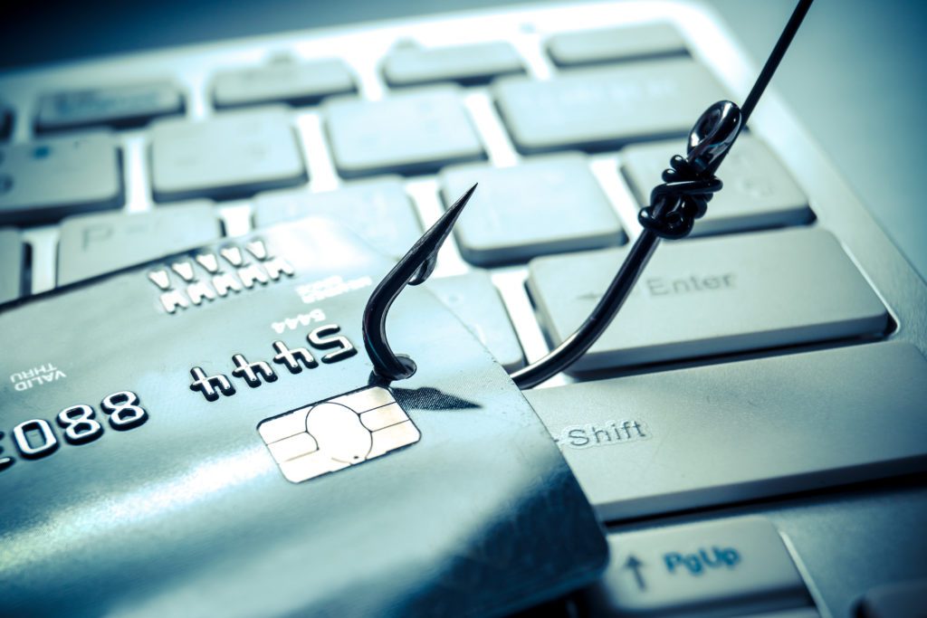 Credit card on a keyboard getting caught by fish hook.