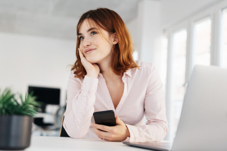 Young woman holding cellphone looking off to the side