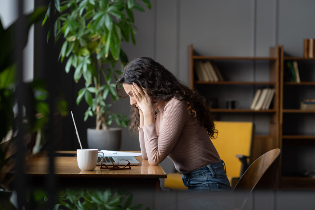 Female in front of a laptop thinking.